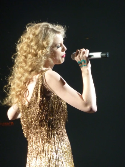 blonde haired woman wearing gold sequins singing on stage