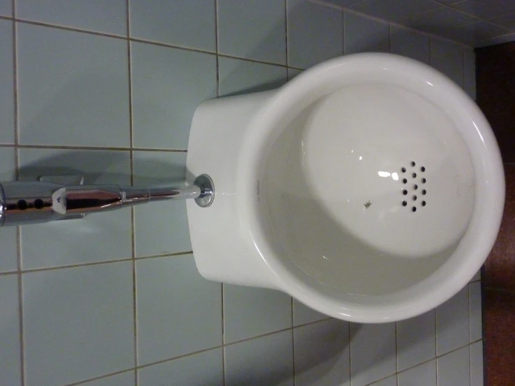 a urinal mounted on a wall with tiled walls