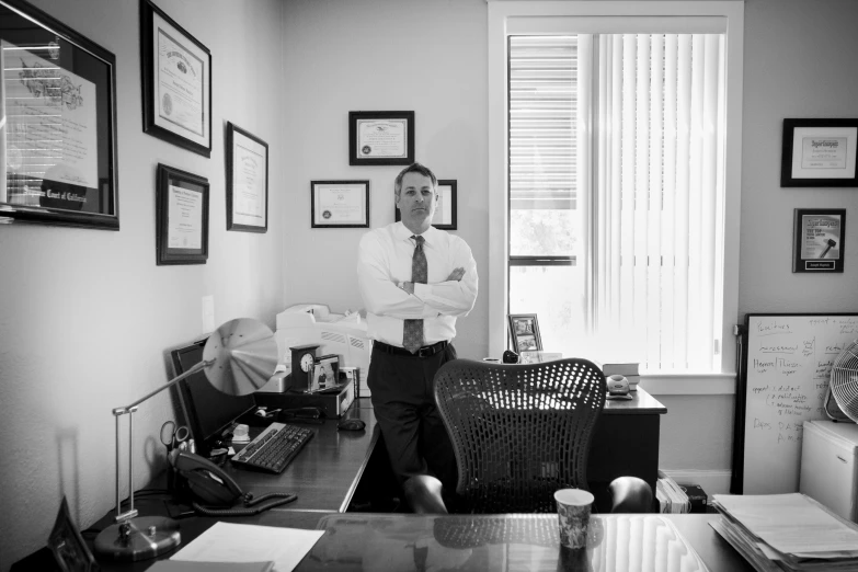 man standing in front of desk next to pictures on wall