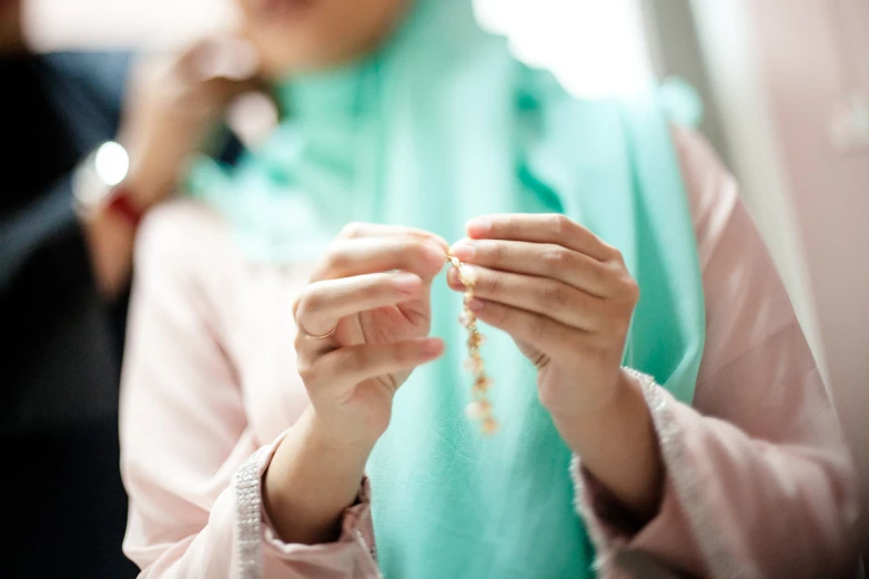 woman with necklace holding small beaded rosary