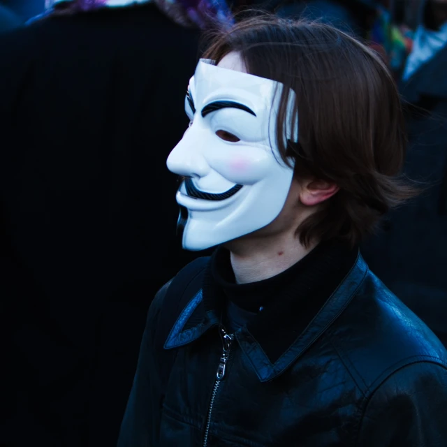 a person wearing a white mask standing in front of a crowd