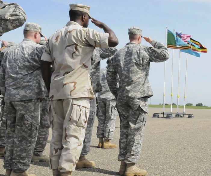 men in military uniform saluting while standing on the ground