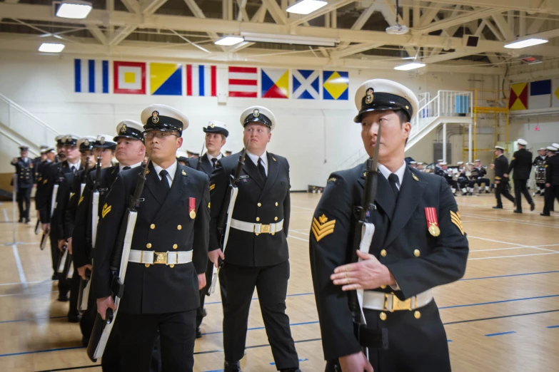 uniformed soldiers stand in formation in an indoor gym