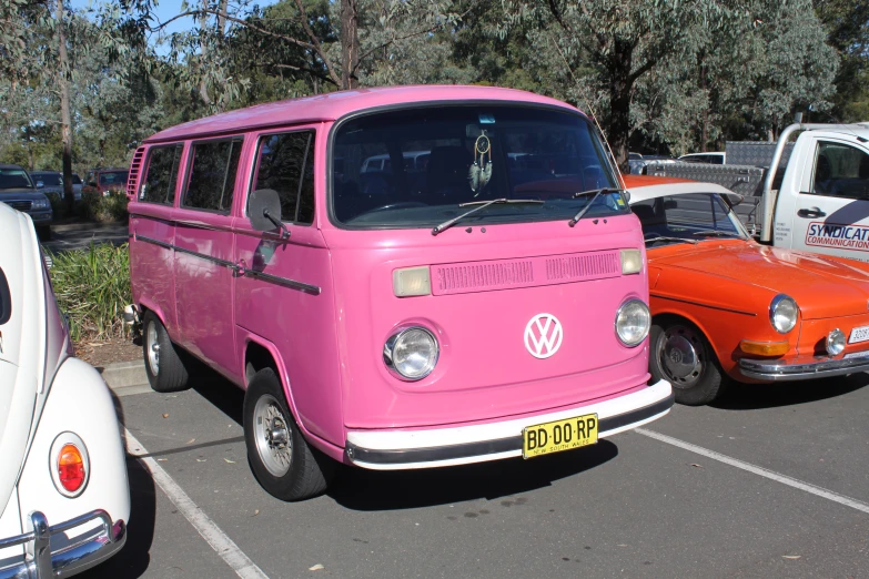 an old, pink and orange volkswagen bus in a parking lot