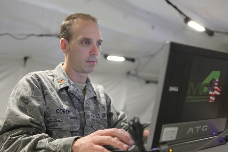 a man in uniform sitting at his desk and working on his computer