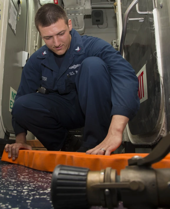 a man with a black uniform working on a piece of orange material