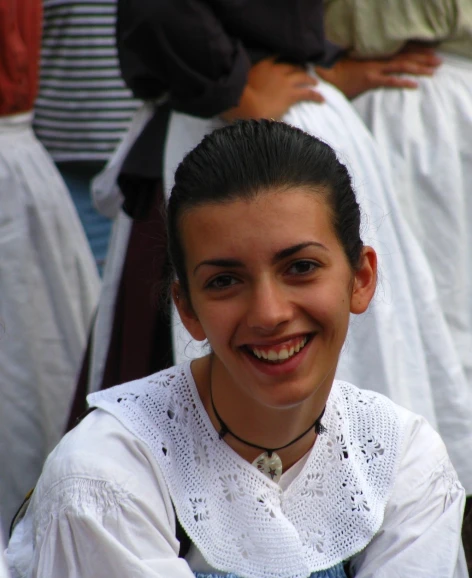 a smiling woman wearing an apron with other people in the background