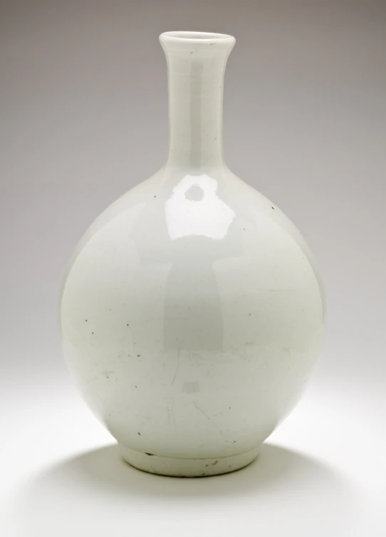 a plain white glass vase sits in a spotlight