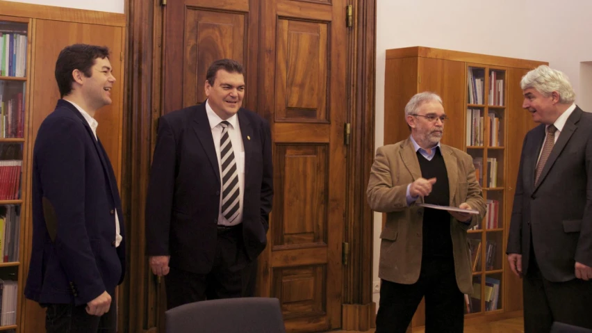 three men dressed in suits talking while looking at soing