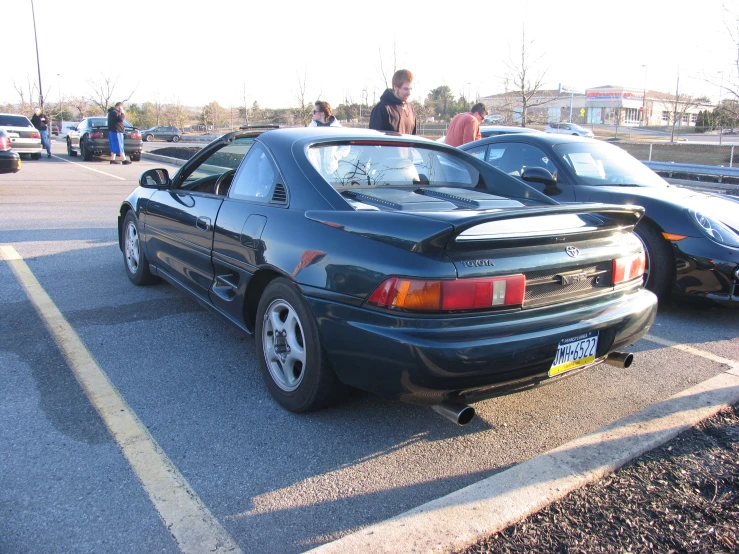 people look at two cars that are parked on the street