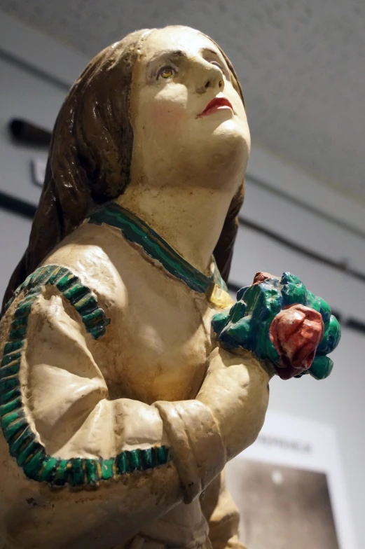 a statuette has a green head and is holding a rose in her left hand