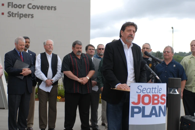 the men are gathered around the man giving his speech