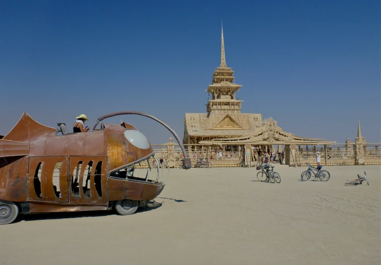 a strange looking vehicle on the desert in front of a building