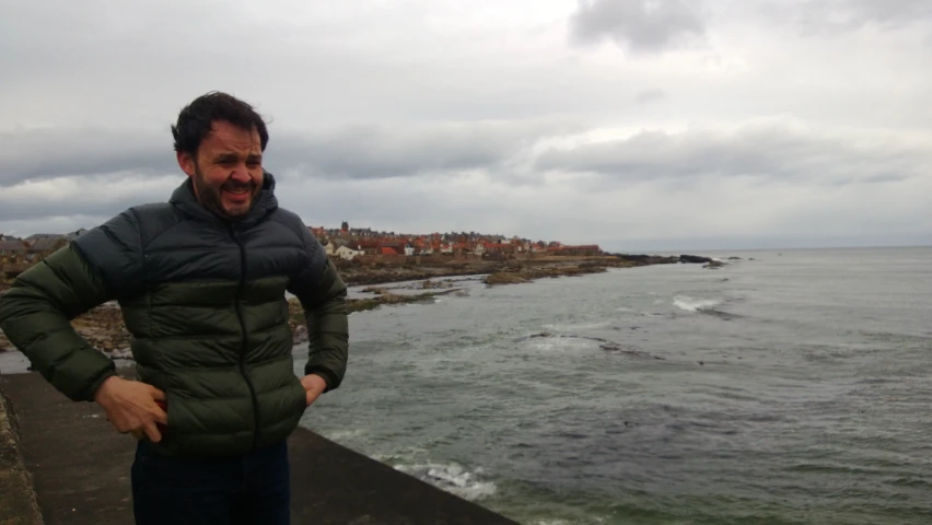 a man posing for the camera next to a body of water