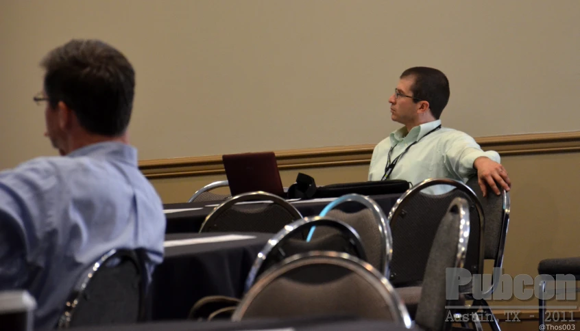 a man standing up in front of a room full of chairs