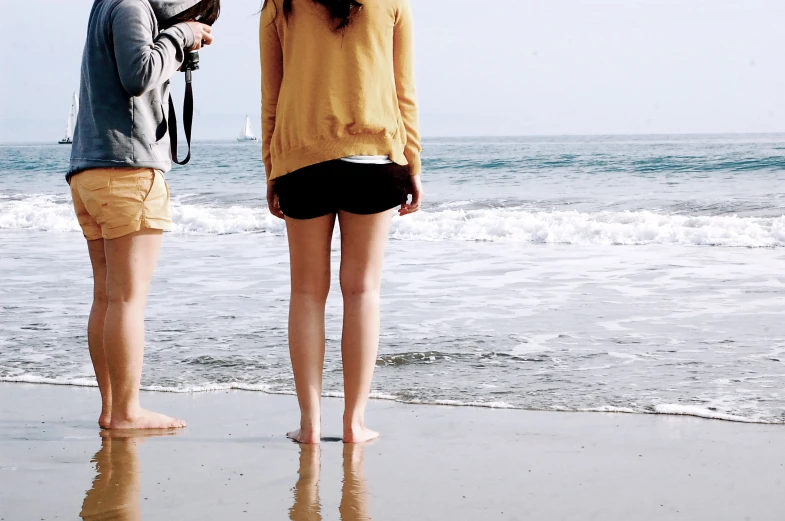 two people stand on the shore by an ocean