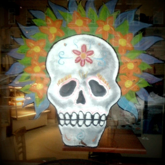 a bright skull with colorful designs is sitting in a window