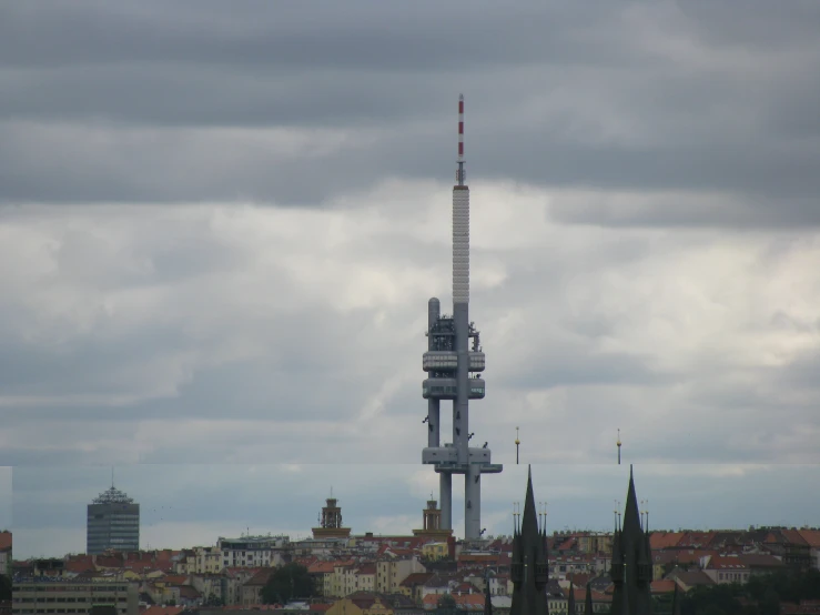 a tall tower towering above the city below cloudy skies