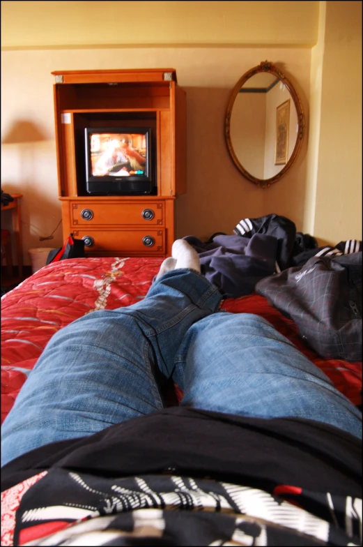 person laying on top of a bed looking at the tv