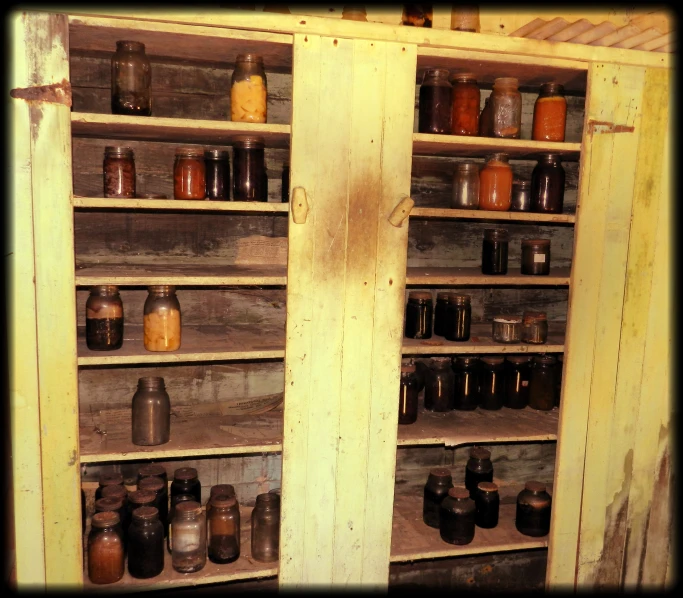 a bunch of jars in a shelf with two doors