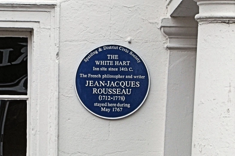 a blue plaque sitting next to a white building