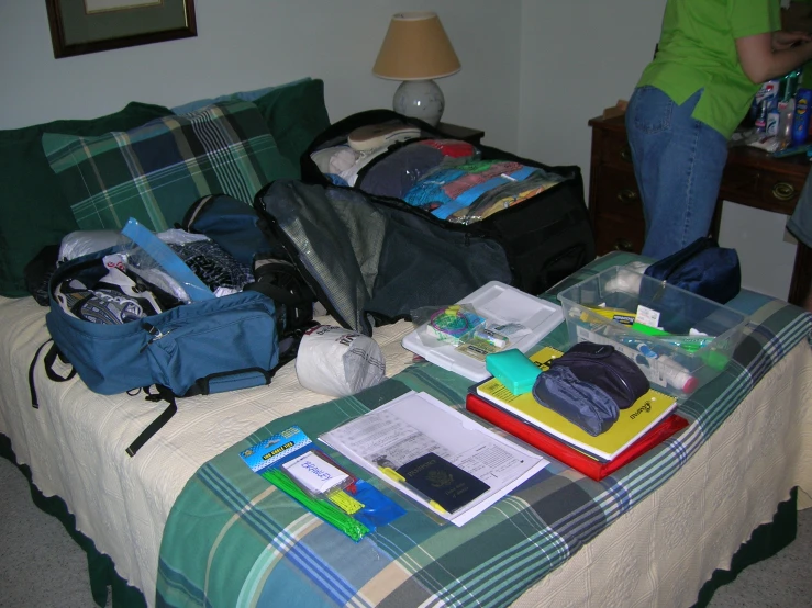 the bed has many folded and packed items on it