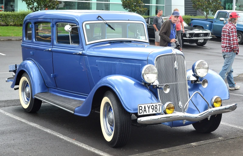 an old blue car parked in a parking lot