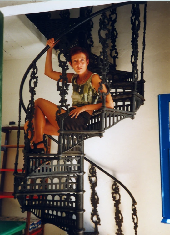 a woman in a green dress is climbing the spiral stairs