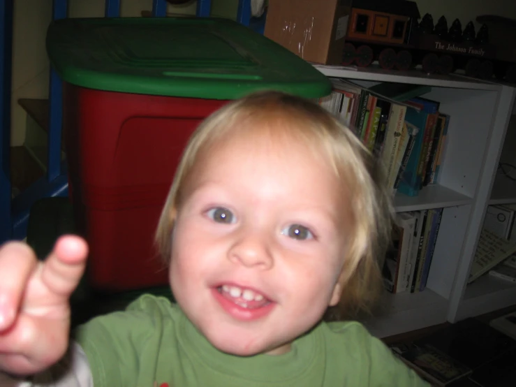 a toddler smiles while standing by a toy truck