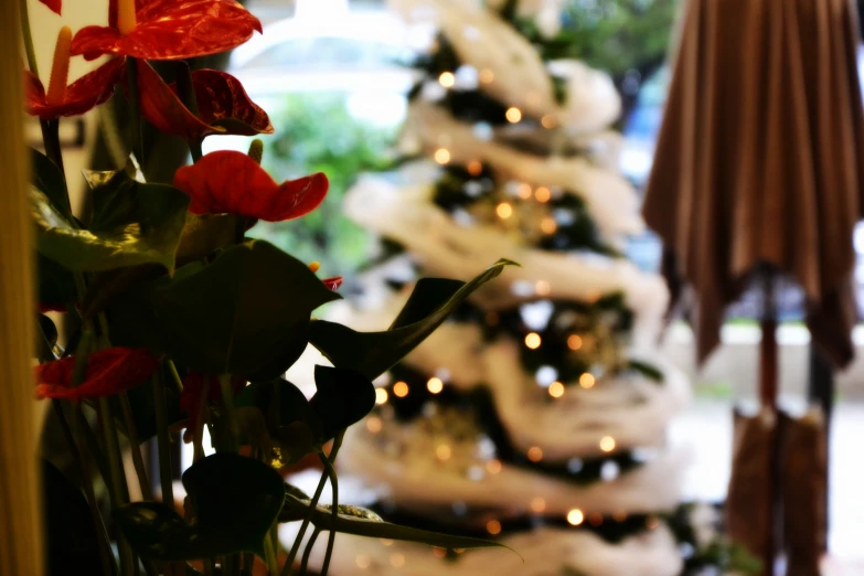 a christmas tree is decorated with ornaments and red flowers