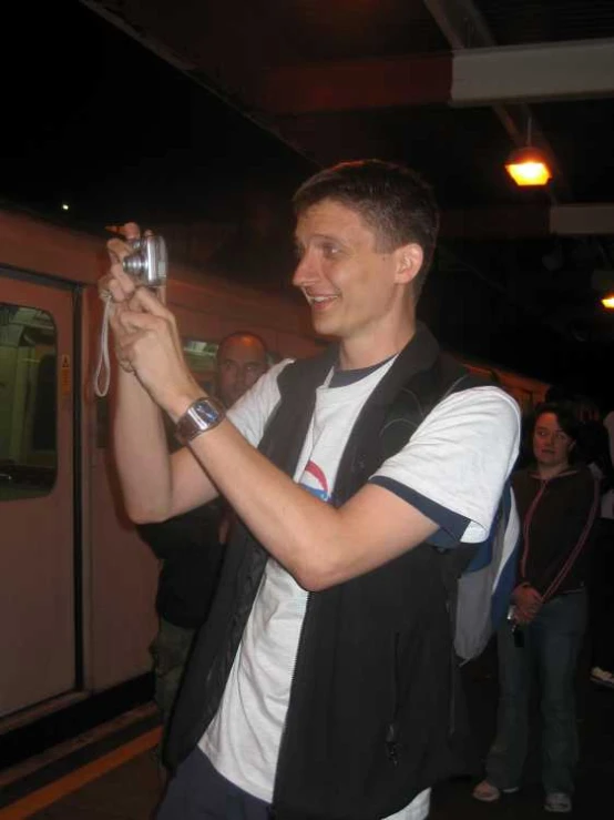 a smiling young man holds a wine glass and takes a selfie