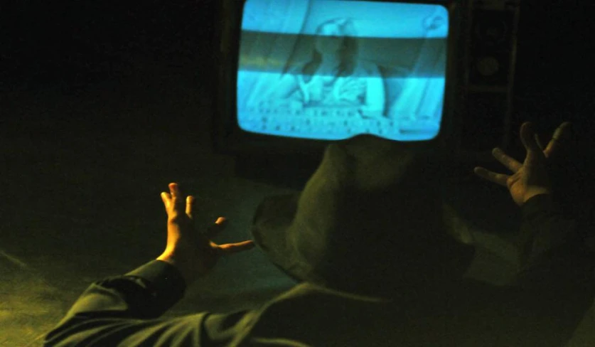 man watching television in the dark with his hand outstretched