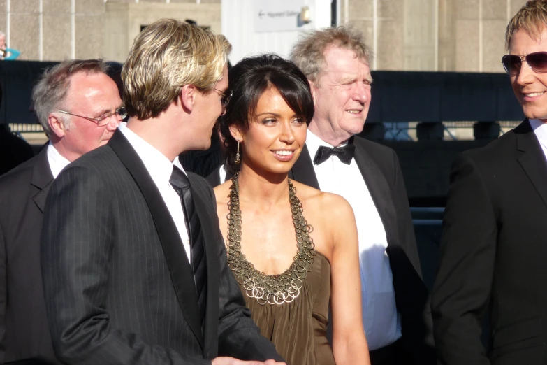 a woman in a gold dress standing between two men