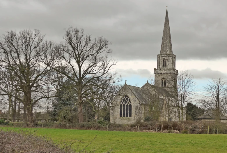 an old church sits in the foreground with trees lining the grass