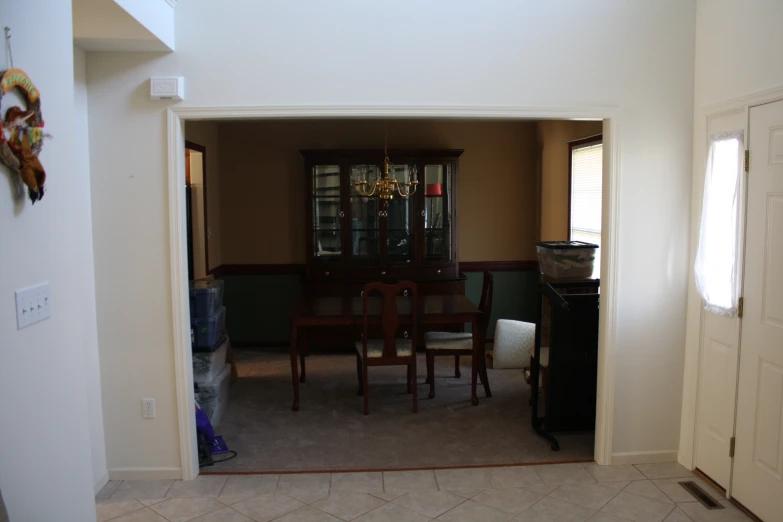 a living area with a door open and a table and chairs with a vase in front