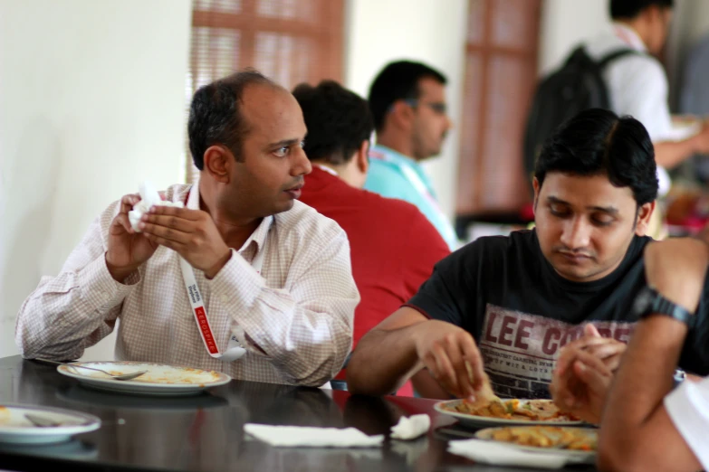 man eating at table, with people looking on