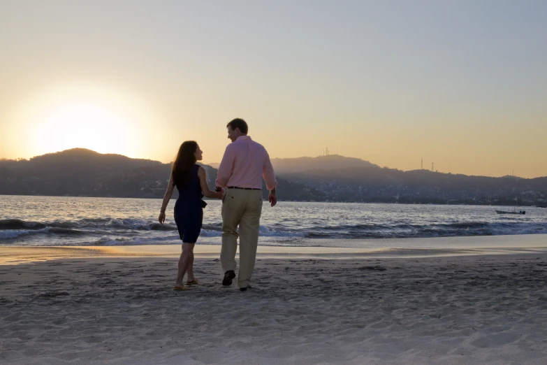 a couple on the beach, walking towards the sunset