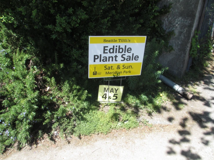 a yellow sign with black lettering stating a plant sale