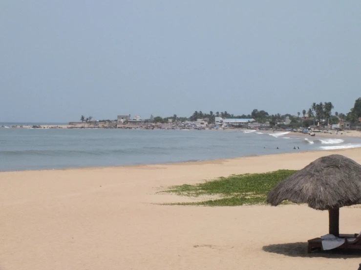 a grass umbrella is on the sandy beach