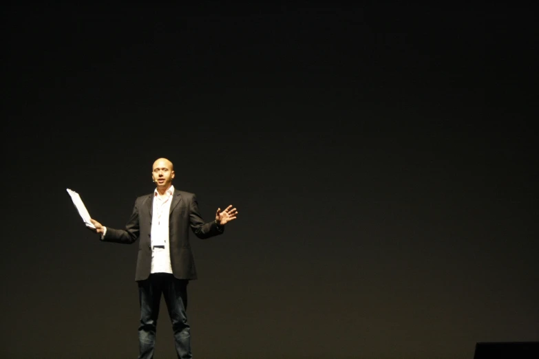 a man standing on stage, wearing a suit and holding a knife in both hands