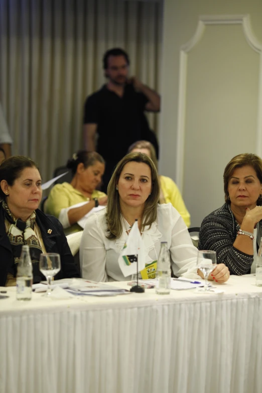 women sitting at tables listening to speakers in a room