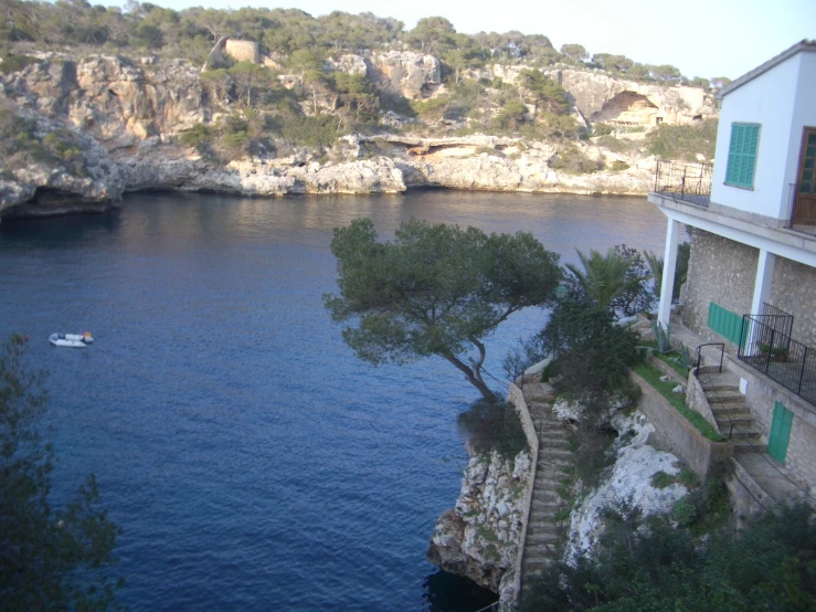 house with open windows overlooking the water and stairs leading to it