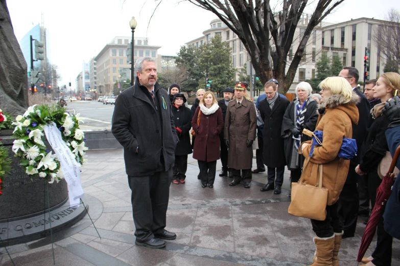 many people gather near a monument with a man standing at it