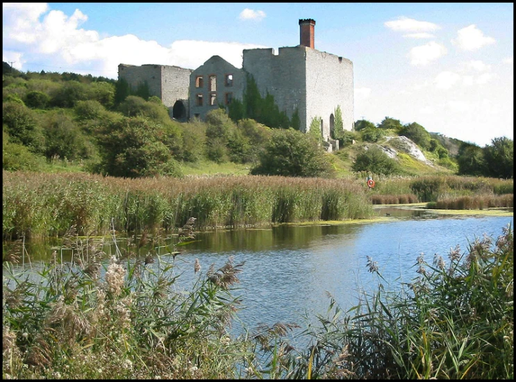 large abandoned house and pond in grassy landscape