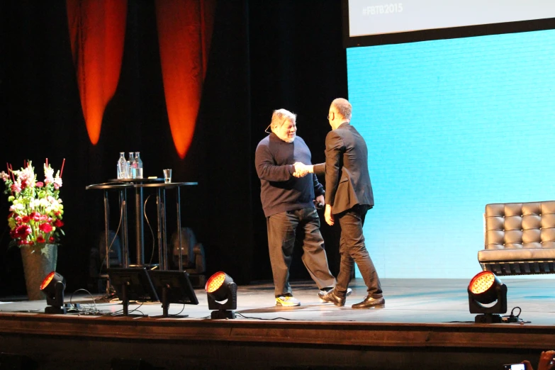 two men on stage talking on the phone