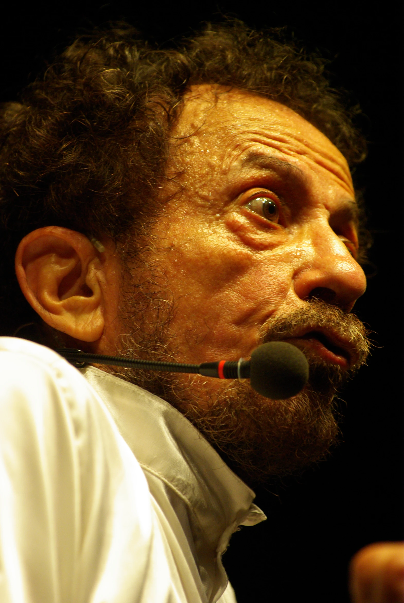 a man with dark hair and beard speaking into a microphone