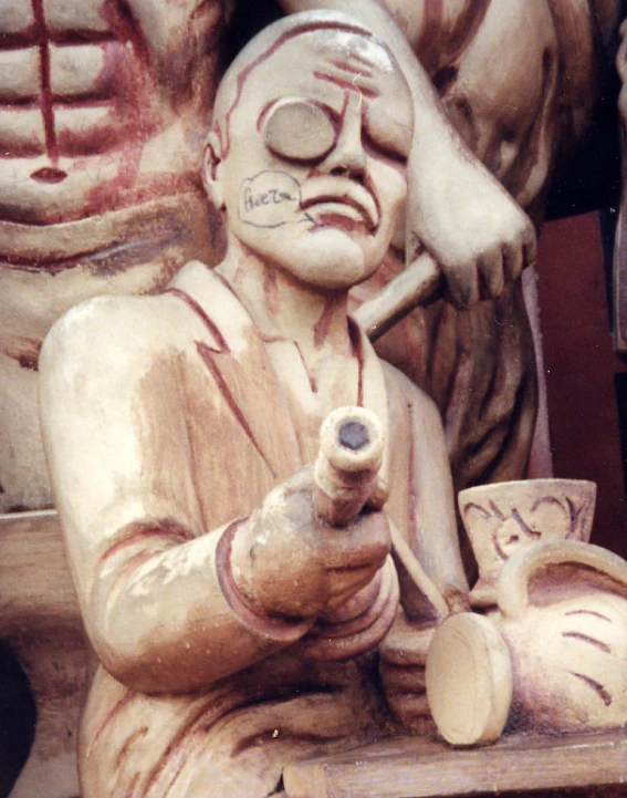 a wooden statue holding a pot with his fingers