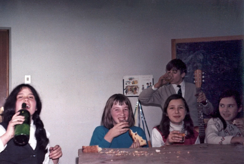 four young women sit at a table and are eating pizza