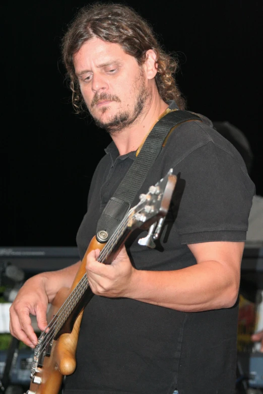 a man holding a guitar on top of a wooden guitar rack