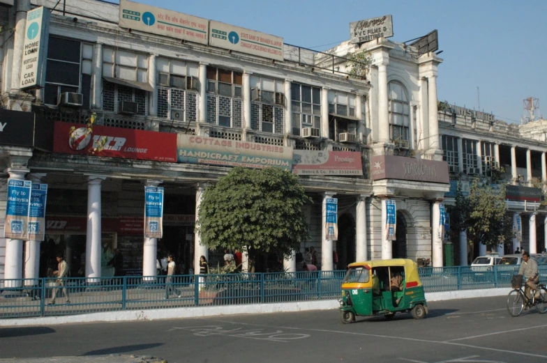 the yellow and green vehicle is driving in front of a building